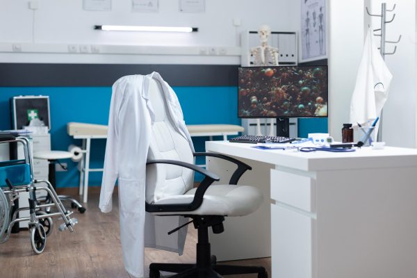 computer-with-covid19-illustration-screen-standing-desk-empty-office-room-during-global-pandemic-modern-hospital-room-equipped-with-professional-medical-instruments-virus-cell-image